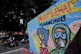  Warga melintas di depan mural bertema Hidup Sehat Lawan COVID-19 di Serengan, Solo, Jawa Tengah, (27/5/2020). | Sumber: ANTARA FOTO/Maulana Surya/aww