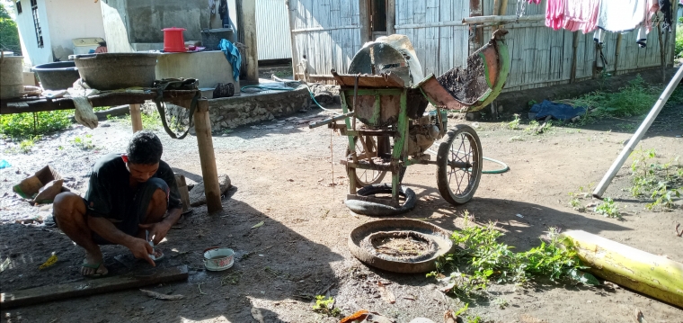 Om Alo sedang mengasah mata pisau alat giling batang pisangnya. Foto: Roman Rendusara