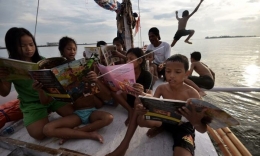 Anak-anak yang sedang membaca buku di Perahu Pustaka. Sumber: hipwee.com