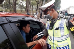 Seorang pengendara saat ditilang polisi di Jalan Benyamin Sueb, Jakarta Utara, karena melanggar aturan ganjil-genap, Rabu (1/8/2018).(KOMPAS.com/Ardito Ramadhan D)