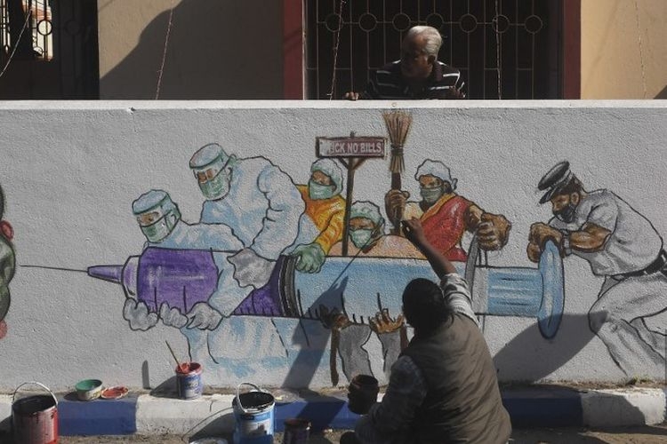 Seorang seniman memberikan sentuhan akhir pada mural yang menggambarkan pekerja garis depan membawa vaksin Covid-19 virus corona di Kolkata pada 2 Januari 2021.(AFP PHOTO/DIBYANGSHU SARKAR via Kompas.com)