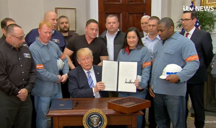 Presiden AS Donald Trump meneken tarif baja dan aluminium didampingi pekerja, pada 8 Maret 2018. (Foto: YouTube/ITV News) 