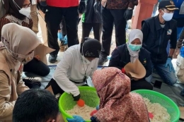 Mensos Tri Rismaharini saat ikut membantu membungkus nasi bagi korban banjir di Jember, Jawa Timur| Sumber gambar : nasional.sindonews.com