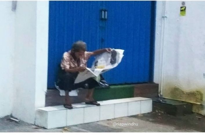 Seorang bapak membaca koran di pinggir jalan (dok.windhu) 