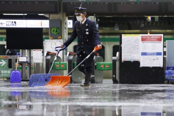 Seorang petugas stasiun membersihkan sisa-sia air akibat gempa bumi sabtu lalu (Sumber: Kyodo News)