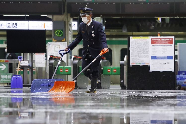 Seorang petugas stasiun membersihkan sisa-sia air akibat gempa bumi sabtu lalu (Sumber: Kyodo News)