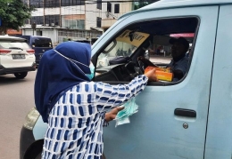 Pemred Sudut Pandang, Umi Sjarifah, saat membagikan nasi kotak dan masker kepada sopir angkot di bilangan Petojo, Jakarta Pusat, Jumat (19/2/2021)/Foto:istimewa