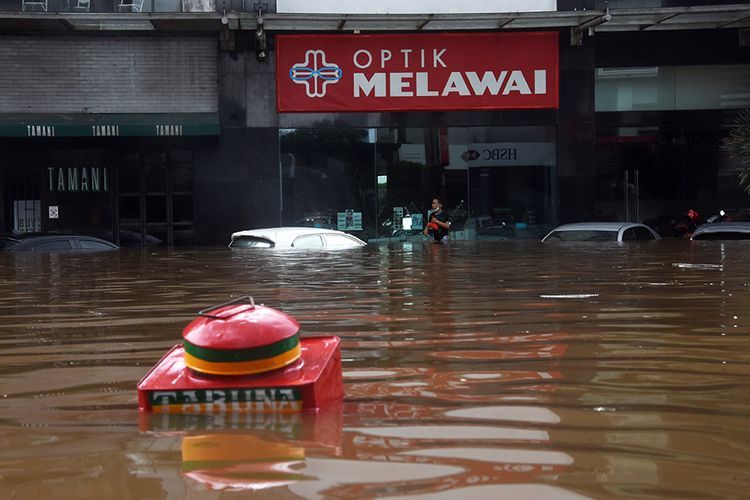 Warga berjalan melewati banjir di kawasan Kemang, Jakarta Selatan, Sabtu (20/2/2021). Banjir yang terjadi akibat curah hujan tinggi serta drainase yang buruk membuat kawasan Kemang banjir setinggi 1,5 meter.(ANTARA FOTO/INDRIANTO EKO SUWARS) [Melalui Kompas.com)