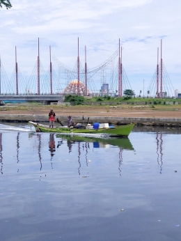 Perahu motor nelayan Makassar menyusur alur Kanal Jongaya dengan latar kawasan CPI/Ft: Mahaji Noesa