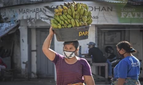 Seorang perempuan buruh panggul menggunakan masker saat bekerja di pasar tradisional.(republika.co.id)