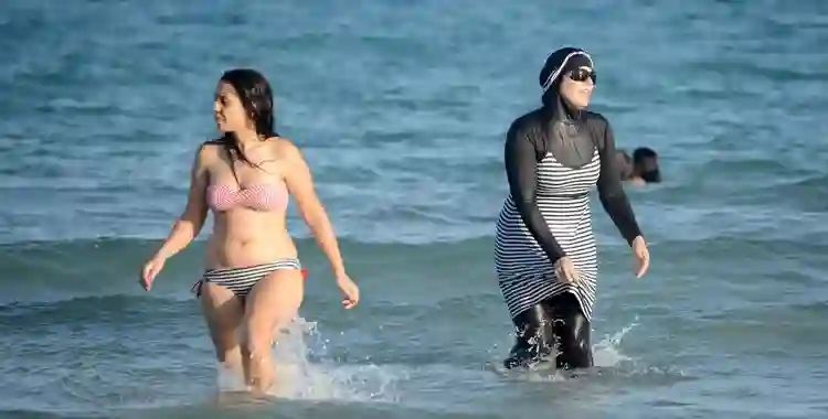 Pemakai bikini (kiri) dan pemakai burkini (kanan) di pantai Tunisia. Foto: Getty images via tokresource.org