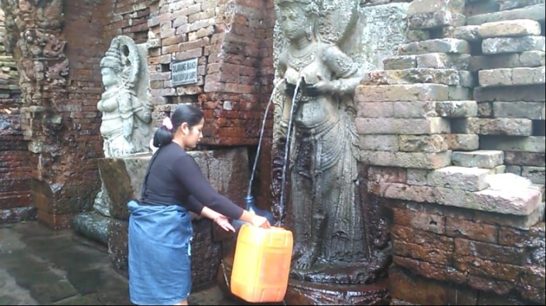 Seorang warga mengambil air dari Candi Belahan atau Sumber Tetek (Foto: wartabromo.com)