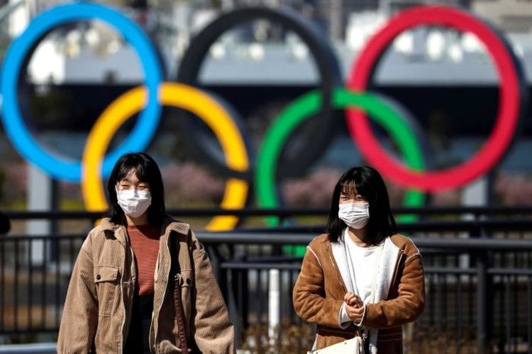 Dua warga berjalan di depan logo olimpiade di Tokyo, Jepang.(REUTERS via ABC INDONESIA/KOMPAS.COM)