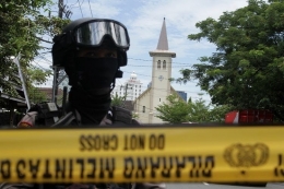 Anggota polisi berjada di ruas jalan menuju Gereja Katedral Makassar yang menjadi lokasi ledakan bom di Makassar, Sulawesi Selatan, Minggu (28/3/2021). Kapolda Sulawesi Selatan Irjen Pol Merdisyam mengatakan ledakan bom di gereja tersebut mengakibatkan satu korban tewas yang diduga pelaku bom bunuh diri serta melukai sembilan orang jemaat dan petugas gereja. ANTARA FOTO/Arnas Padda/yu/foc.(ANTARA FOTO/ARNAS PADDA)