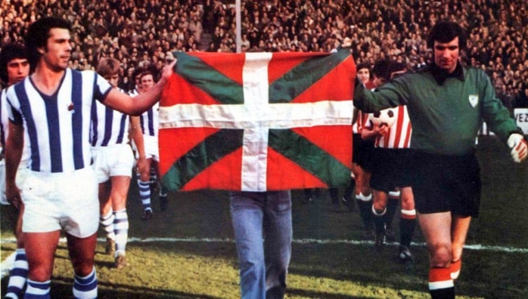 Kapten Inaxio Kortabarra dari Real Sociedad (kiri) dan Jos ngel Iribar membawa bendera Basque yang masih ilegal sebelum derby pada bulan Desember 1976. | Courtesy of Real Sociedad via The Guardian