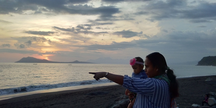 Istri dan anak sedang memandang senja di tepi pantai. Foto: Roman Rendusara