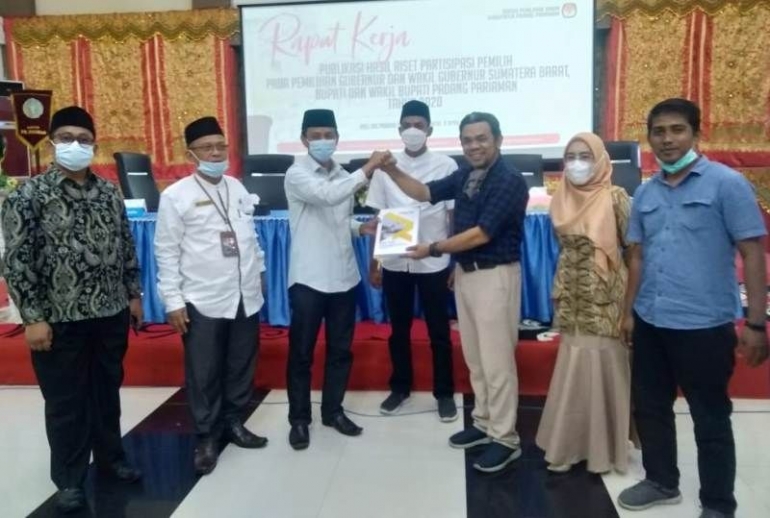 Dr. Eka Widia Putra menyerahkan hasil riset dan kajiannya terkait partisipasi pemilih dalam Pilkada tahun lalu ke Ketua KPU Padang Pariaman Zulnaidi dalam rapat kerja KPU. (foto dok damanhuri)