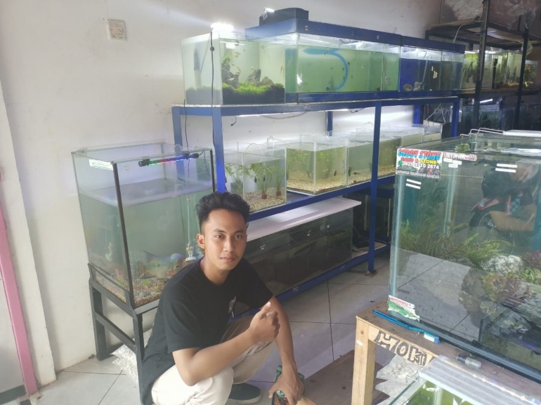 Swafoto bersama akuarium berisi beragam ikan, termasuk channa