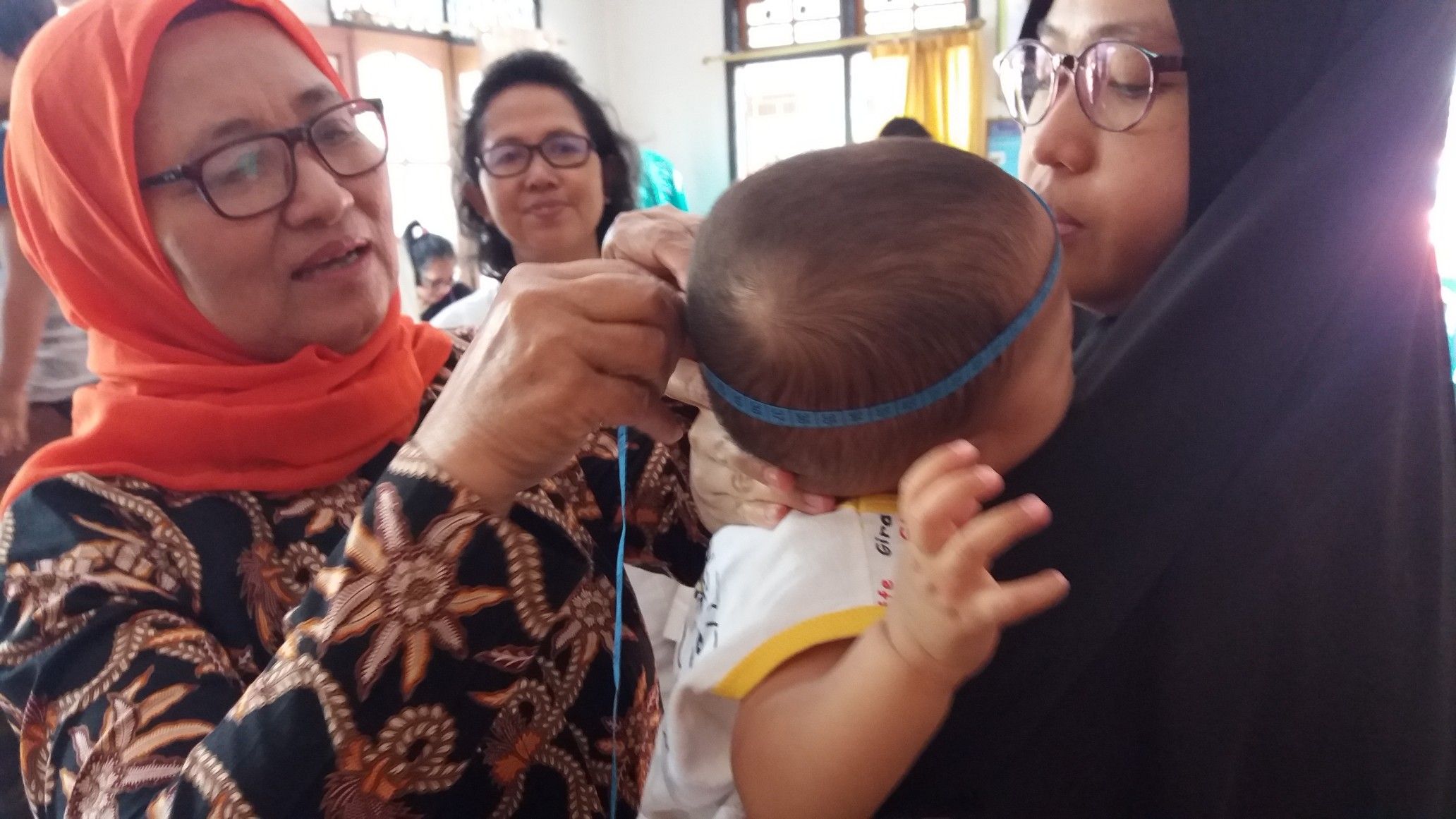 Kader posyandu sedang mengukur lingkar kepala balita untuk memantau tumbuh-kembangnya (Dokumentasi Pribadi)