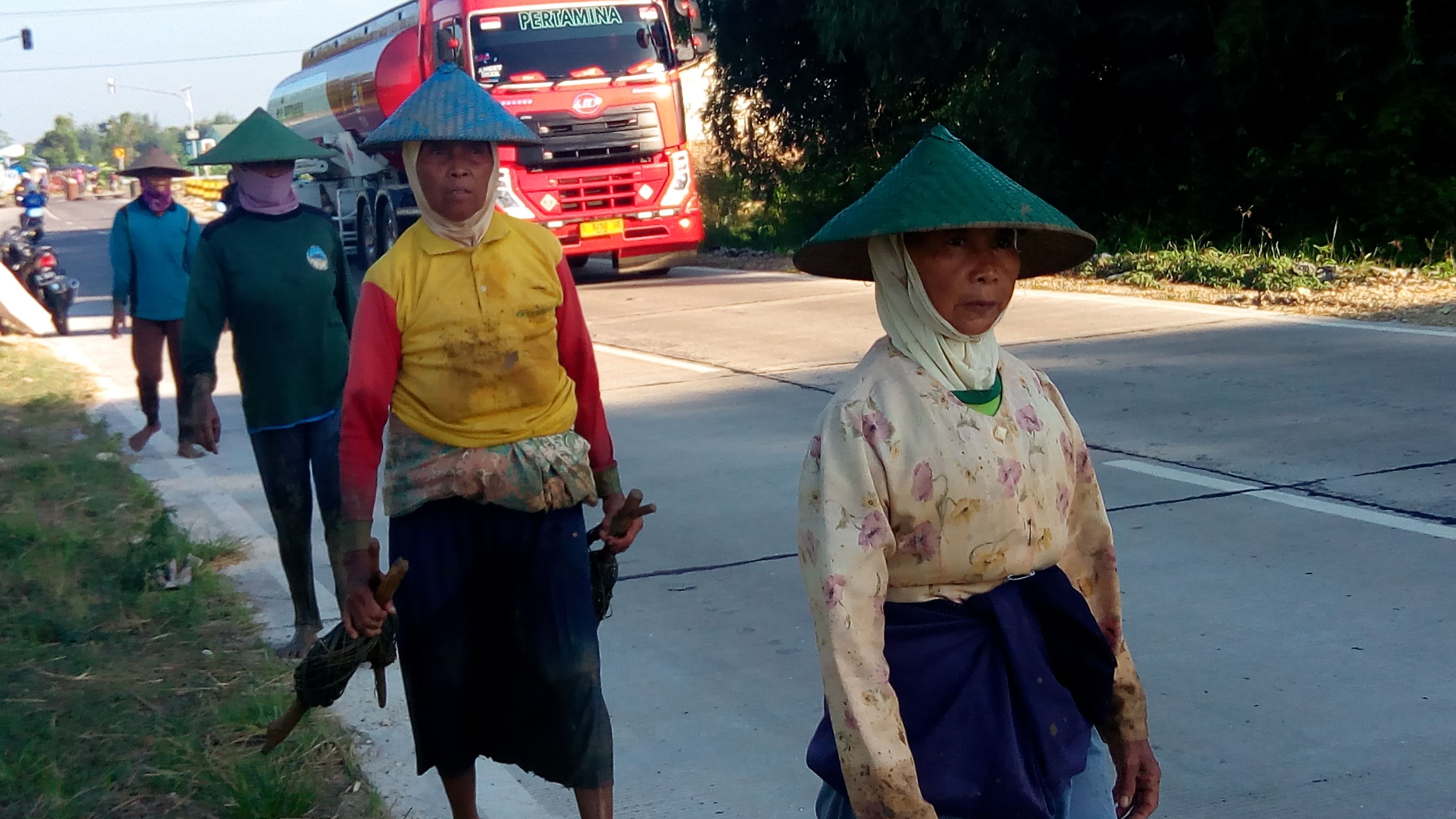 PULANG. Berangkat dini hari, pulang menantang matahari. Berjalan tanpa alas kaki, berlomba dengan laju kendaraan. (dok. IH)