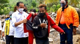 Presiden Jokowi memberikan jaket miliknya dan mengenakannya kepada seorang pengungsi di desa Amakaka, Kabupaten Lembata (foto : regional.inews.id)
