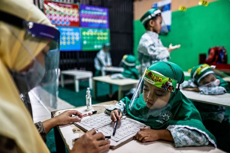 Guru menggunakan masker dan pelindung wajah saat menerangkan pelajaran dalam kelas tatap muka di TK An-Nuur, Jakarta Selatan, Selasa (4/8/2020). Uji coba pembelajaran tatap muka ini berlangsung dengan menjalankan protokol kesehatan Covid-19.(KOMPAS.com/GARRY LOTULUNG) 
