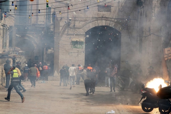Warga Palestina melarikan diri ketika polisi menembakkan granat kejut selama bentrokan di kompleks Masjid Al-Aqsa | Foto dari Reuters/Ammar Awad
