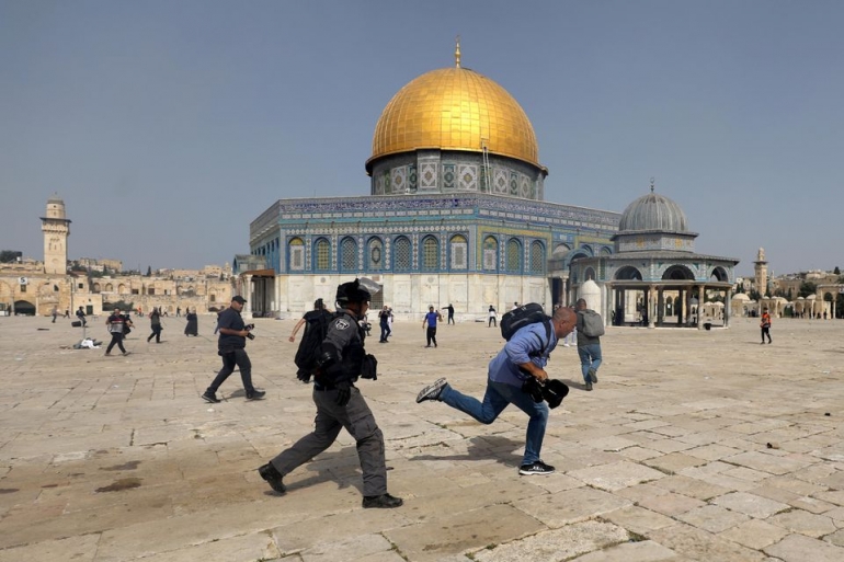 Seorang anggota polisi Israel mengejar seorang warga Palestina di kompleks Masjid Al-Aqsa pada 10 Mei 2021 | Foto dari Reuters/Ammar Awad