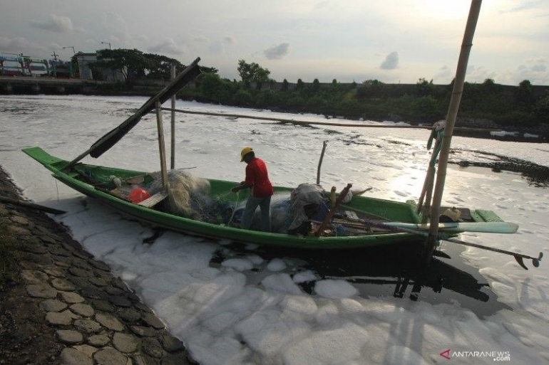 Nelayan beraktivitas di muara Sungai Tambak Wedi yang permukaannya penuh busa putih di Surabaya, Jawa Timur, Minggu (29/3/2020). (ANTARA FOTO/Didik Suhartono/foc)