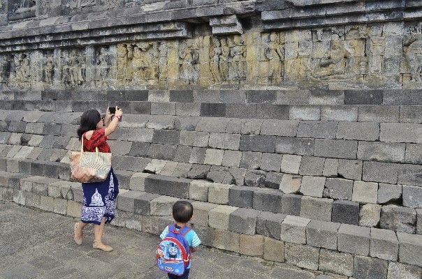Saya sedang memotreti relief Borobudur. Anak saya mengawasi saya dari samping. Foto: Dokumen pribadi.
