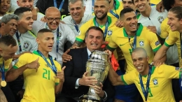 Jair Bolsonaro (Presiden Brasil) bersama trofi Copa America 2019 dan Skuad Timnas Brasil (Goal.com)