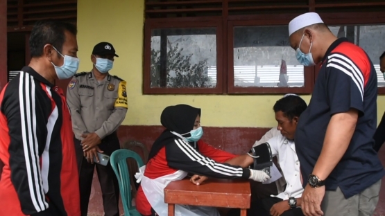 Kepala Desa Belaras (kopiah putih), Kepala Pustu Belaras (baju kaos lengan panjang), dan babinkatibmas mengawasi kegiatan vaksinasi. (foto : Elvidayan