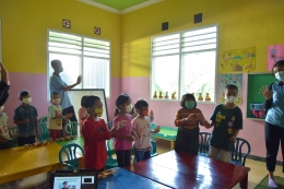Foto Tim KKN UM dan anak-anak Desa Gunungronggo mempraktekan cara melindungi diri ketika terjadi bencana alam melalui lagu dan gerakan