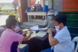 Seorang pekerja di Barangay Camarines Sur memverifikasi daftar penerima Ayuda agar tak terjadi kesalahan. - Sumber: Rappler