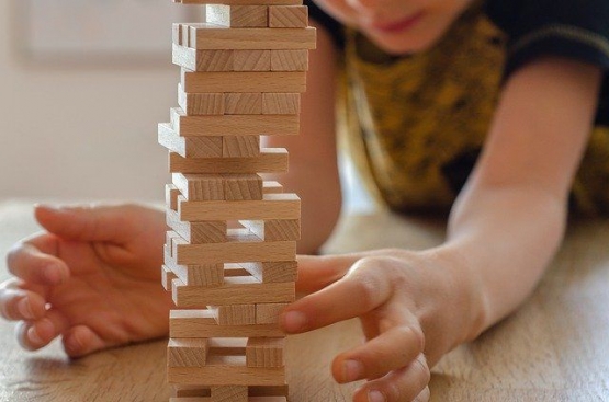 Seorang anak memilih balok agar bangunan tinggi Jenga tidak roboh. Sumber : Pixabay.