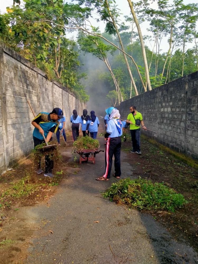(Foto 2. Anggota KKN dan Warga saling bergotong royong membersihkan rumput)