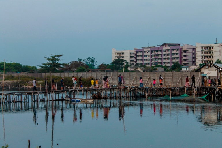Warga berjalan di jembatan penyeberangan di sore hari di Pantai Marunda. (Jonas/Mahasiswa)