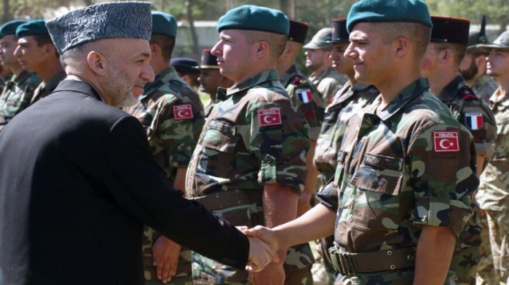 Afghan President Hamid Karzai (L) shakes hands with a Turkish soldier of the NATO-led International Security Assistance Force (ISAF) during a transfer of command ceremony at the ISAF headquarters in Kabul, Oct. 5, 2006. - SHAH MARAI/AFP via Getty Images