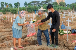 Keluarga menaruh bunga kepada peti jenazah korban Covid-19 di TPU Rorotan Cilincing, Jakarta Utara, Minggu (18/7/2021). (Jonas/Mahasiswa)