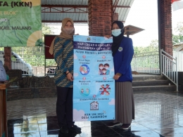 Penyerahan banner protokol kesehatan kepada sekretaris Desa Kasembon