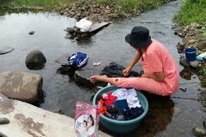 Seorang ibu rumah tangga yang sedang memanfaatkan air sungai untuk mencuci baju, foto: matrapendidikan.com