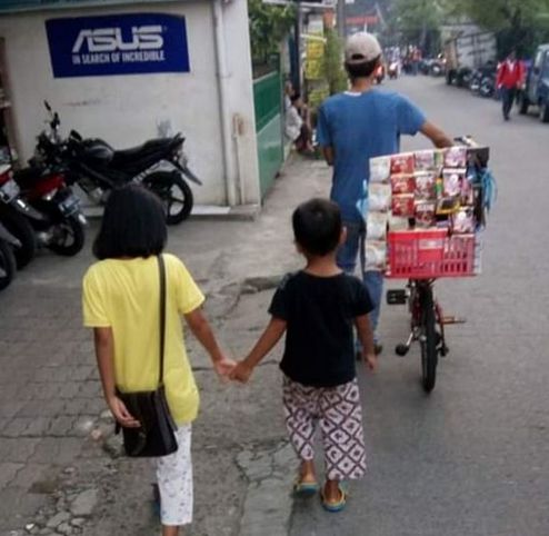Penjual kopi keliling dengan sepeda bersama dua anaknya di jalan menuju Stasiun Pondok Cina. (Foto: Norman Meoko)