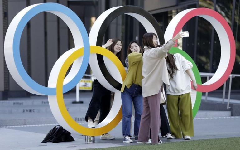 Sejumlah warga berfoto di dekat logo Olimpiade di depan Museum Olimpiade di Tokyo | Sumber: Bloomberg 