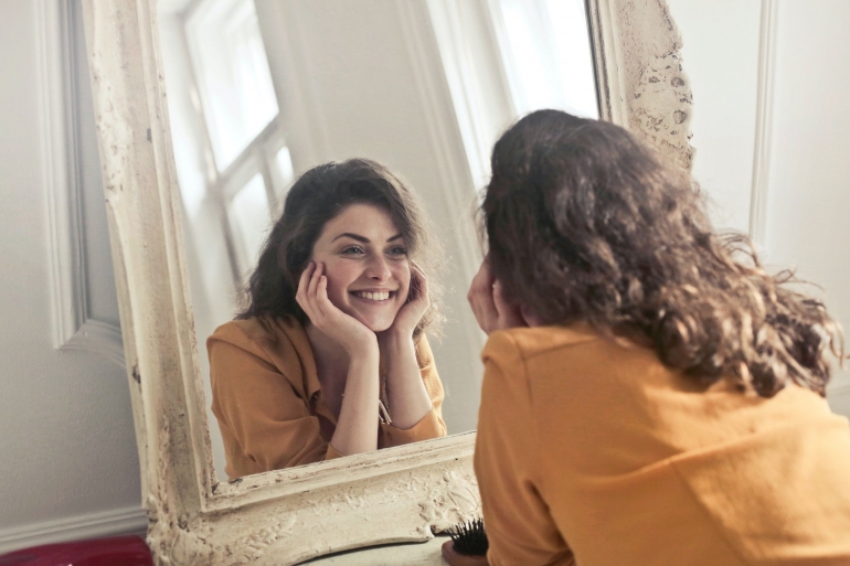 Seorang gadis yang sangat terlihat bahagia di depan cermin. (sumber: pexels/Andrea Piacquadio)