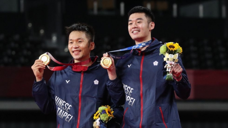 Senyum semringah Lee Yang/Wang Chi-Lin berkalungkan medali emas Olimpiade Tokyo: bwfbadminton.com