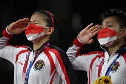 Pasangan ganda putri Indonesia Greysia Polii (kiri) dan Apriyani Rahayu (kanan) memberi hormat dengan medali emas bulu tangkis ganda putri pada upacara Olimpiade Tokyo 2020 di Musashino Forest Sports Plaza di Tokyo pada 2 Agustus 2021. (Foto: AFP/ALEXANDER NEMENOV via Kompas.com)
