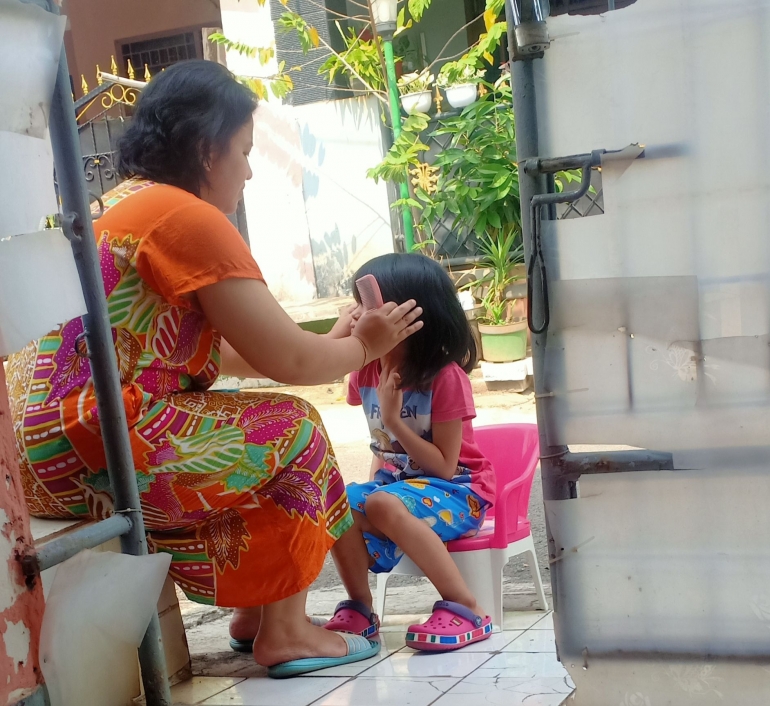 Cucu saya Senandung (7 tahun) dirapikan rambutnya oleh ibunya hanya menggunakan gunting dan sisir di rumah (foto Nur Terbit)