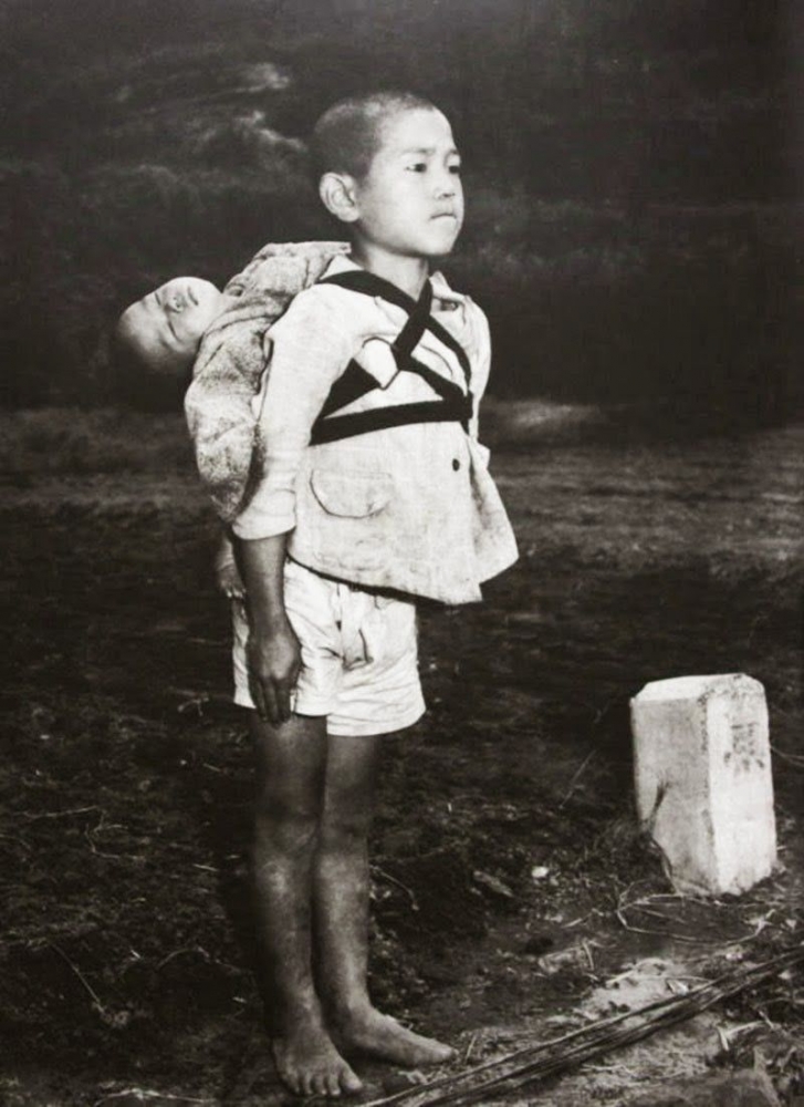 Anak laki laki itu dengan tegar menggendong adiknya yang telah meninggal dan menunggu giliran menyerahkan adiknya pada petugas kremasi. Photo : Rare Historical 