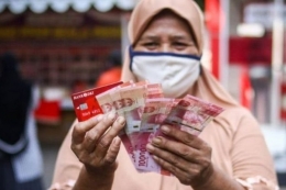 Warga menunjukkan uang bantuan sosial tunai atau BST usai mengambil di ATM Bank DKI, Jakarta, Selasa (20/7/2021).(ANTARA FOTO via KOMPAS.com)