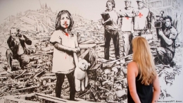 Mural karya Banksy sebagai kritik terhadap media yang mengabarkan korban perang dan serangan teroris. | (mh/as) via amp.dw.com